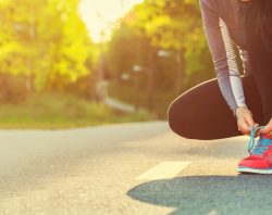 Female runner tying her shoes preparing for a run a jog outside